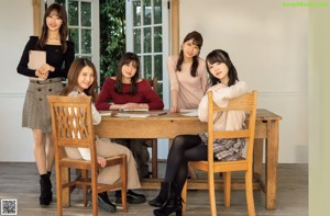 A group of three women sitting at a wooden table.