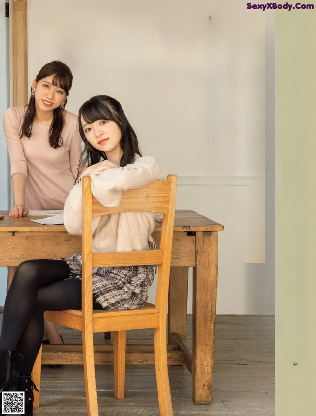 A couple of women sitting at a wooden table.