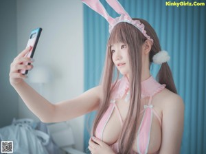 A woman in a pink bunny costume leaning against a wall.