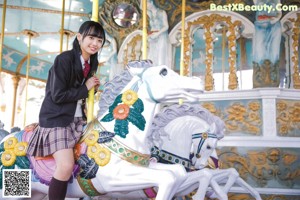 A young woman in a school uniform smiles at the camera.