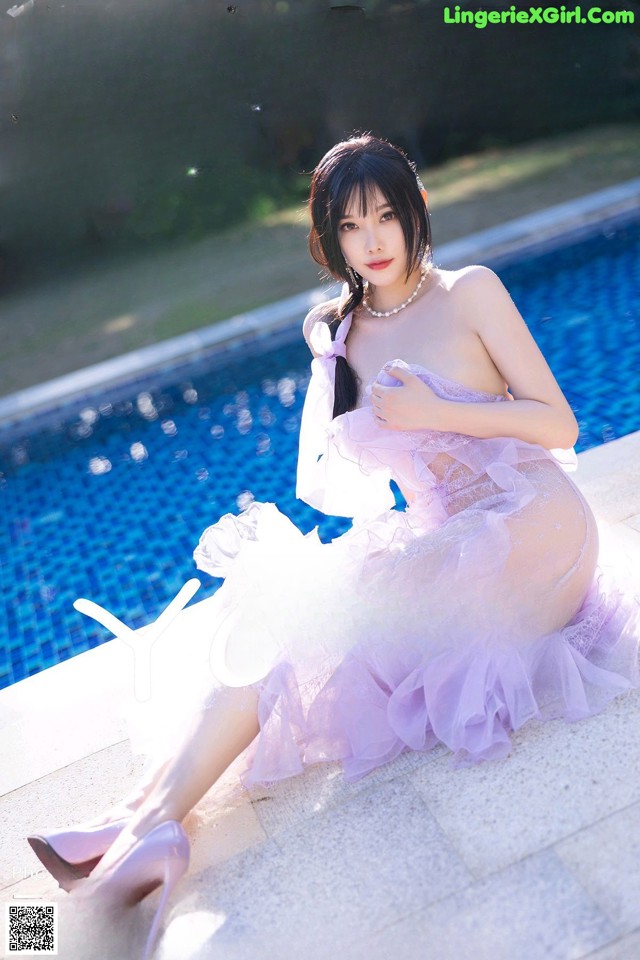 a woman in a purple dress sitting next to a swimming pool