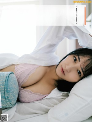 A woman laying on top of a bed next to a picture of herself.