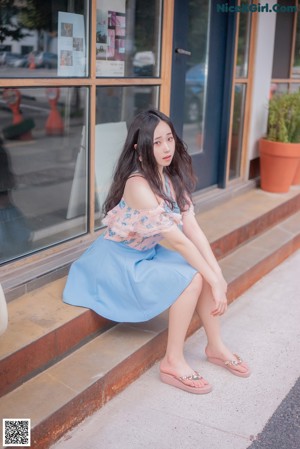 A woman sitting on a stone bench in a park.