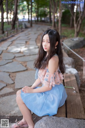 A woman in a blue skirt is walking down a sidewalk.