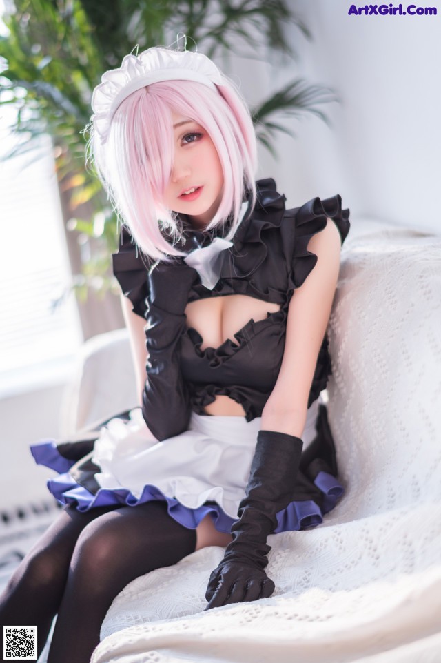 A woman with pink hair sitting on a white couch.