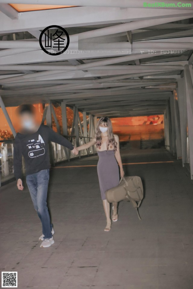 A man and a woman walking under a bridge holding hands.