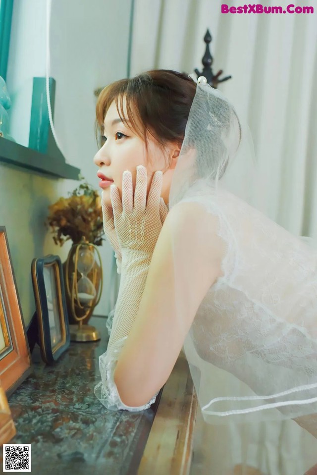 A woman in a wedding dress sitting at a table.