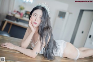 A woman in a white lingerie sitting on the floor.