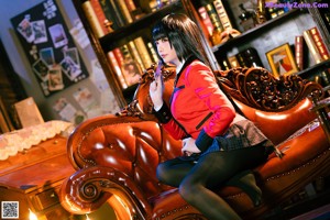 A woman sitting on top of a red couch.