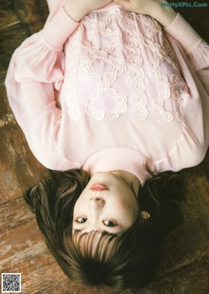 A woman laying on a wooden floor under a blanket.