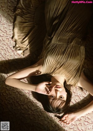 A woman laying on a wooden floor under a blanket.