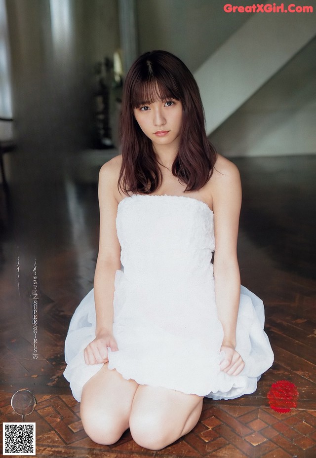 A woman in a white dress sitting on the floor.