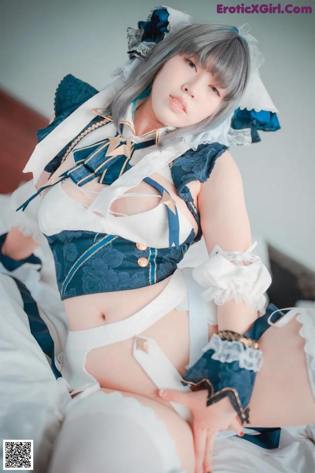 A woman in a blue and white outfit sitting on a bed.