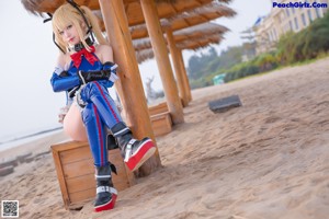 A woman in a blue and red outfit sitting on the sand.