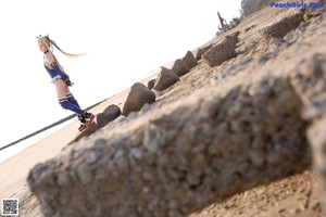 A woman in a blue and white outfit sitting on a sandy beach.