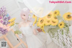 A woman in a white dress holding a bunch of flowers.