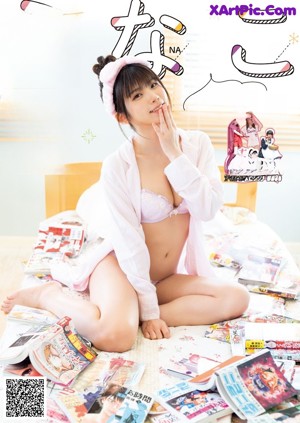 A woman in a pink robe holding a stack of books.