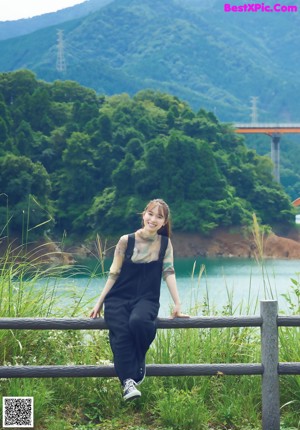 A woman standing in a field with a backpack.