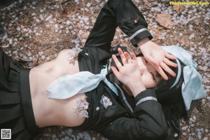 A woman in a white shirt and black stockings crouching on the ground.