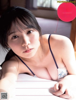 A woman in a white bra and panties sitting on a bed.