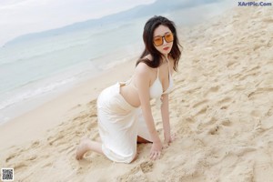 A woman in a white dress standing on a beach.