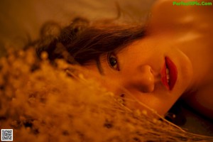 A naked woman sitting on a bed holding a bunch of flowers.