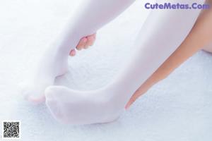 A woman in white stockings is sitting on a bed.
