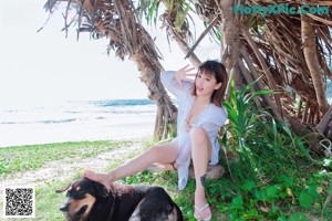 A woman in a white tank top sitting on a chair.