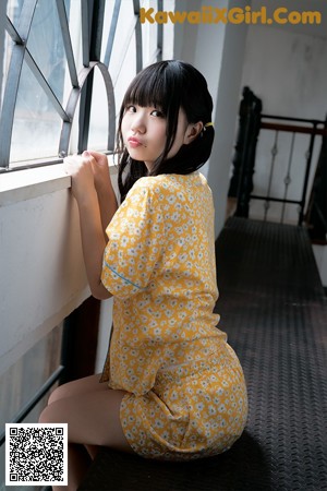 A woman sitting on top of a wooden dresser.