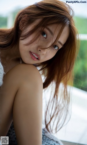 A woman laying on a wooden floor next to a window.