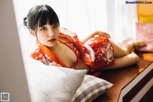 A woman in a red kimono sitting on the floor.
