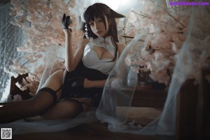 A woman sitting on top of a bed next to a tree.