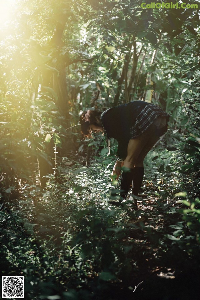 A woman bending over in the middle of a forest.