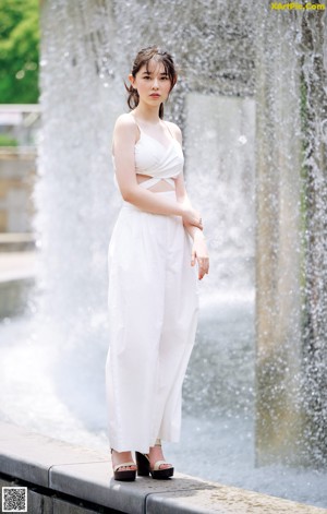 A woman wearing a white crop top with a palm tree on it.