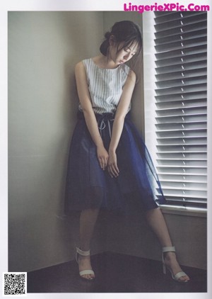A woman sitting on a couch in a blue skirt.