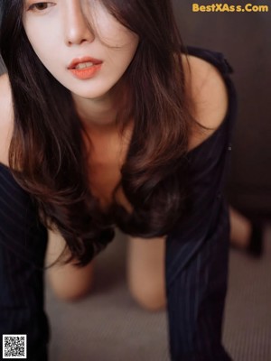 A woman in a black dress and high heels is sitting on the floor.