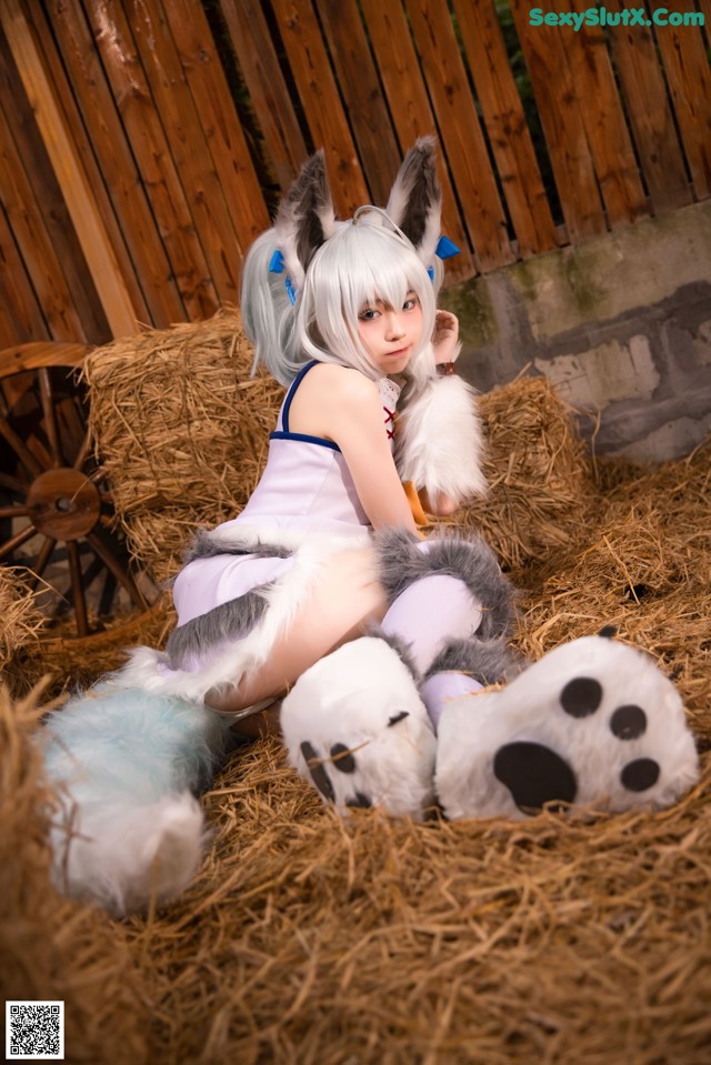 A woman in a bunny costume sitting on a pile of hay.