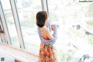 A woman with a tattoo on her leg is sitting on a bed.