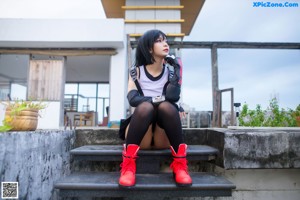 A woman in a black and white outfit sitting on some steps.