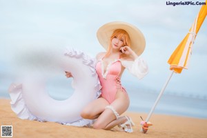 A woman in a pink bikini and a straw hat on the beach.