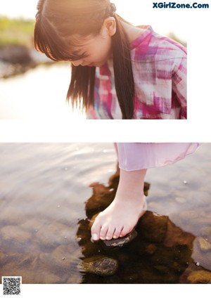 A woman standing on a rock by the water.