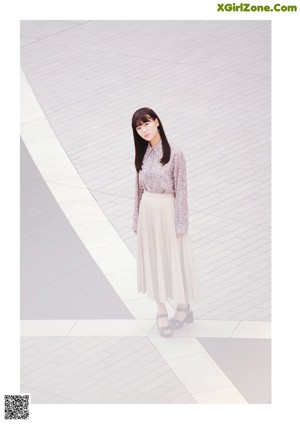 A woman in a long dress standing on a city street.