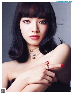 A woman with long black hair wearing a necklace and a ring.