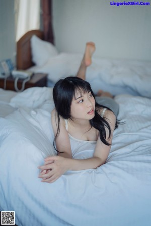 A young woman leaning against a wall with her hand on her chin.