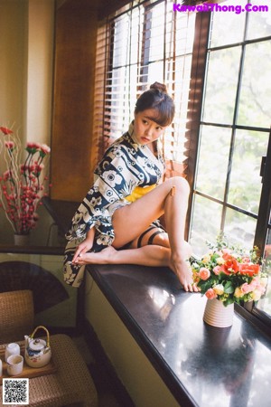 A woman in a kimono sitting on a window sill.