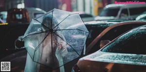 A woman wearing a face mask standing in the rain.