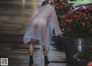 A woman walking down a sidewalk in the rain at night.