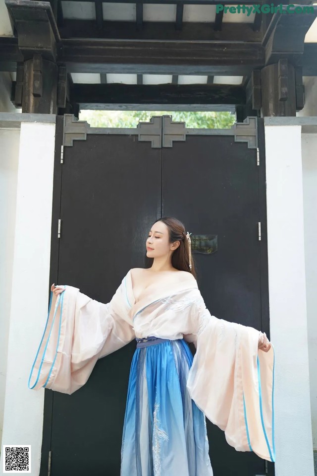 A woman in a blue and white dress standing in front of a door.